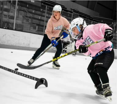 Coach guiding a young hockey player through an on-ice drill