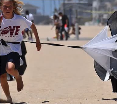 Athlete sprinting on the beach with a resistance parachute